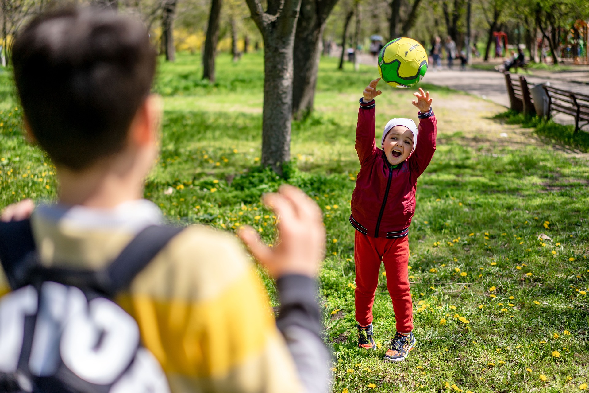 Bilden visar ett barn som kastar boll. Med roliga uteleksaker, som fotbollar, springcyklar, sparkcyklar och scooters skapar du roliga utelekar.